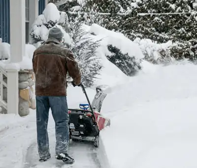 Residential snow removal technician using a snow blower to clear a home driveway and walkway in Madison, WI